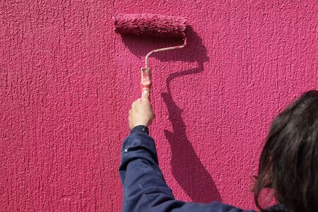 Painting of red wall with paint rollerの写真素材
