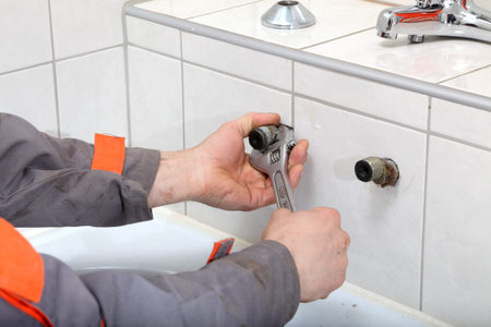 Plumber hands fixing water pipe with spanner
