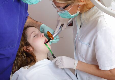 Female dentist and assistant using dental UV curing lightの写真素材