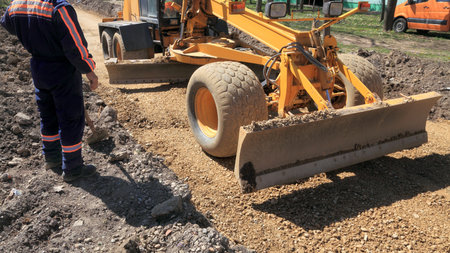 Grader working at road construction site and workerのeditorial素材