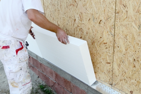 Worker placing styrofoam sheet insulation to the wall Worker placing styrofoam sheet insulation to the wall