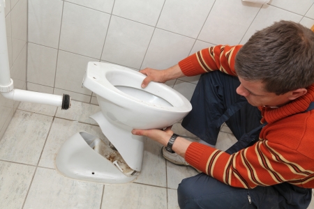 Plumber replacing broken toilet in a washroomの写真素材