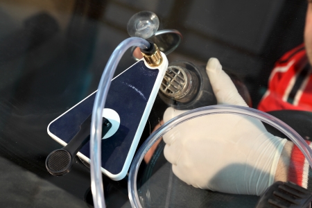 Mechanic using repairing equipment to fix damaged windshieldの写真素材