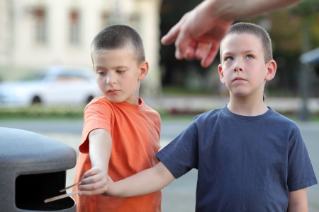 Parent teaching  young boys throwing rubbish to containerの写真素材
