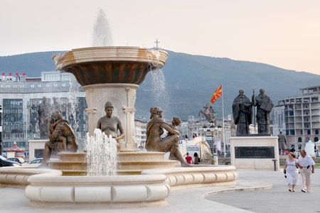 SKOPJE, MACEDONIA - JULY 26  Water fountain of the Mothers of Macedonia, with Cyril and Methodius monument in background and tourist walking July 26, 2013 part of Skopje 2014 reconstruction  project のeditorial素材