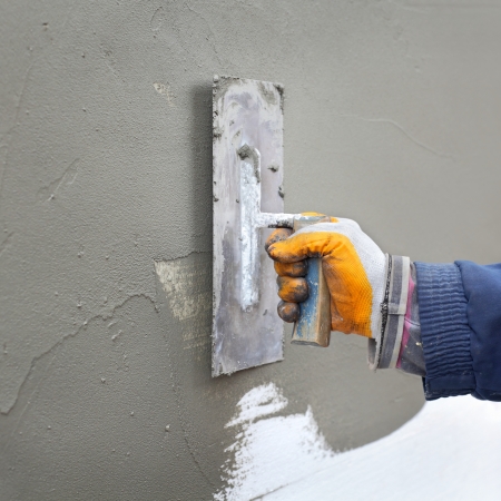 Worker spreading  mortar over polystyrene insulation with trowelの写真素材