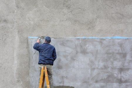 Worker spreading mortar with trowel to polystyrene insulation of wallの写真素材