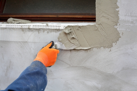 Worker spreading  mortar over polystyrene insulation with trowelの写真素材