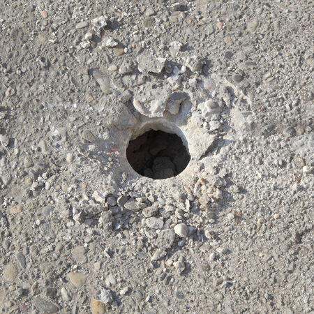Closeup of hole in concrete after demolishing with jackhammer tool at construction siteの写真素材