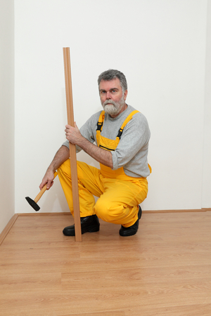 Worker hold batten for laminate floor and hammer,  floating wood tileの写真素材