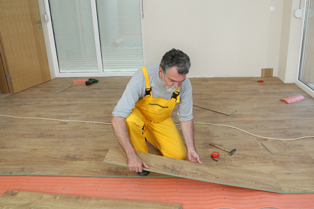 Adult Male Worker Installing Laminate Floor Floating Wood Tile