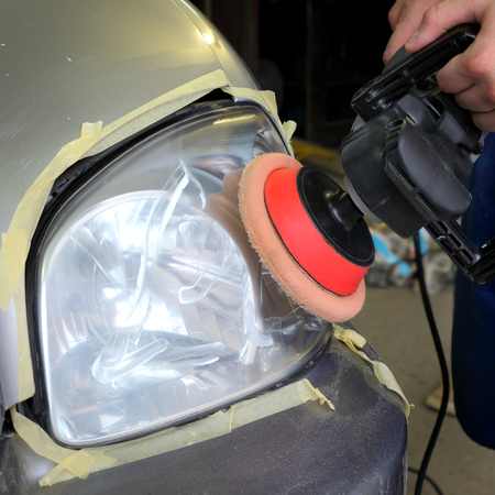 Repairing of  modern car headlight, worker hand with toolの写真素材
