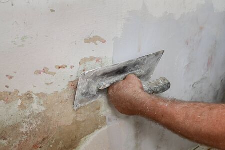Worker spreading  plaster to damaged wall, repairing worksの写真素材