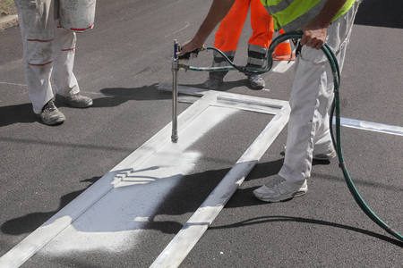 Worker spraying pedestrian crosswalk at a streetの写真素材