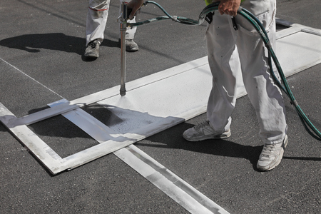 Worker spraying pedestrian crosswalk at a streetの写真素材