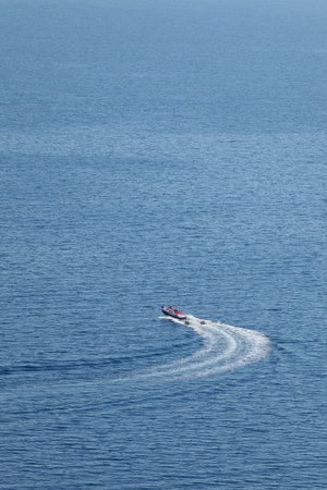  Inflatable donutboats being pulled by a speedboat,  shoot from high distance and from above, Greece