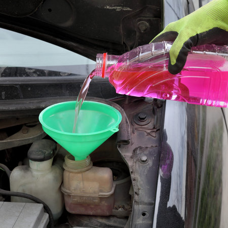 Automotive, car servicing, mechanic pouring fresh antifreeze to engineの写真素材