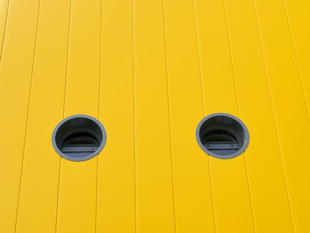 New yellow metal panel wall of building with two round windowsの写真素材