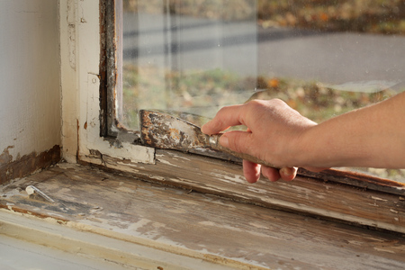 Worker removing oil window glazing putty using putty knife tool, old window restorationの写真素材