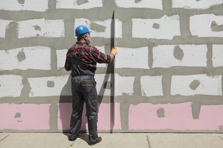 Worker control  polystyrene insulation of wall with level toolの写真素材