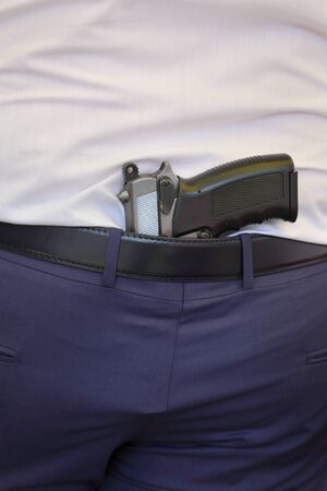 Gun behind belt in pants in the back of a manの写真素材