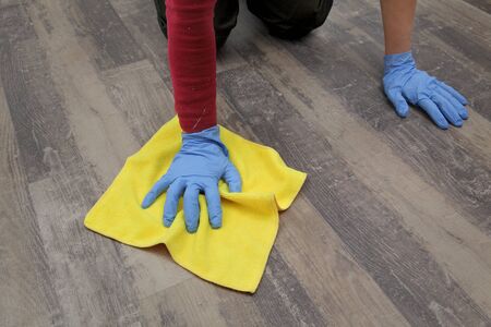 Adult woman kneeling and cleaning laminate floor using ragの写真素材