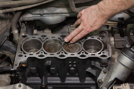 Car mechanic examining cylinder block of engine after disassemblyの写真素材