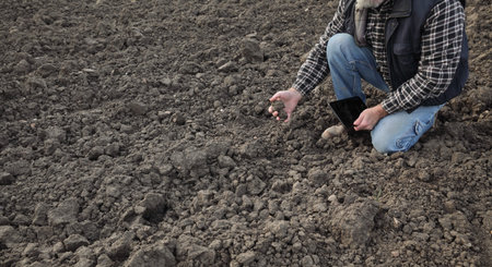 Agriculture, farmer or agronomist examining quality of soil in field using tablet