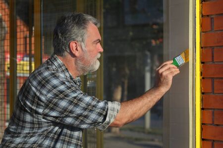 Adult worker painting metal security window netting to yellow colorの写真素材
