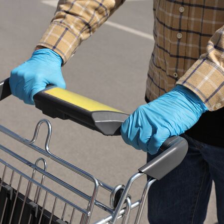 Hands in protective gloves pushing shopping carts, corona virus basic protection, selective focus on handの写真素材