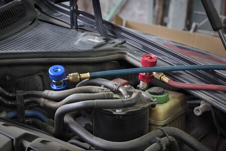 Charging of air condition unit at modern car, closeup of equipment conected to car engine, red and blue clutch couplingsの写真素材
