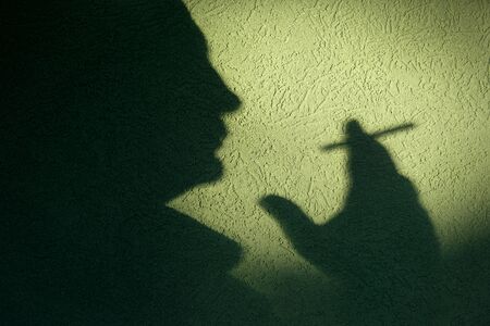 Shadow of adult man holding cigarette in hand and smokingの写真素材