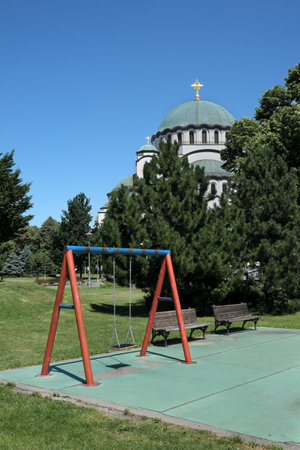 BELGRADE, SERBIA - MAY 30 2020: Empty children playground with Saint Sava church in background,...