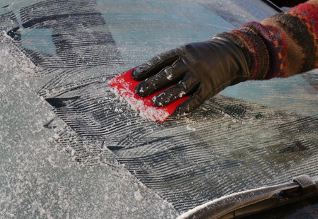 Winter scene, human hand in glove scraping ice from windshield of carの写真素材