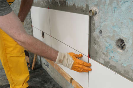 Worker placing ceramic tile to wall in a kitchen or bathroomの写真素材