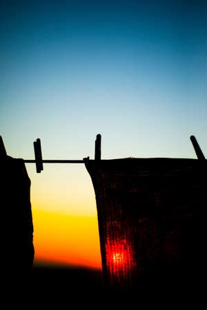 The sun shines through the fabric. Sunset. Dawn. The laundry dries outside. clothespins.の写真素材