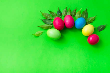 Pattern of colored eggs and green leaves on a green background. Copy space for text. Bright colors. Easter.の写真素材