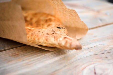 Eastern bread in a paper bag on a wood table. Tandoor lavash. cake.