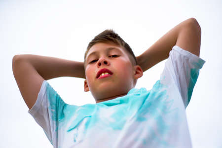 The boy looks down and hands behind his head. Tired and thoughtful look.の写真素材