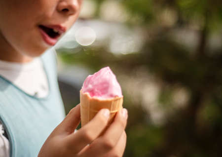 Pink ice cream in a waffle cup in children's hands.の写真素材
