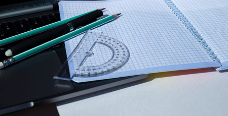 Stationery and squared notebook on laptop keyboard.