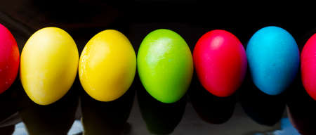 Bright, multi-colored eggs lie in a row on a rectangular black ceramic dish. Easter. minimalism.の写真素材
