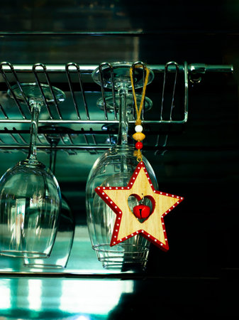 A wooden star with a bell hangs on a wine glass hanger. Waiting for Christmas.