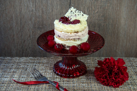 A delicious piece of cake with raspberries and white chocolate. Red plate and fresh fruit.