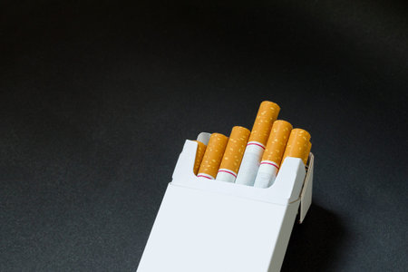 a neatly cigarettes in a white wrap lying on the ground with black backgroundの写真素材