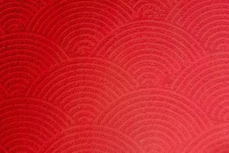 Red textured surface with repeating semi-circular wave patterns, resembling traditional Japanese...