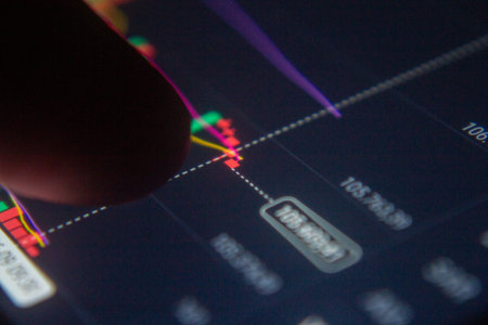 A finger touches a screen displaying a colorful financial chart with market data.