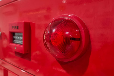 A close-up of a red fire alarm system with a warning light and emergency button.