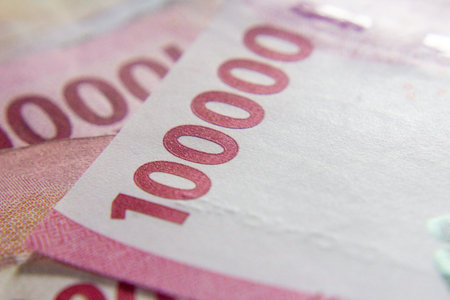 Close-up of Indonesian 100,000 Rupiah banknotes in pink tones.