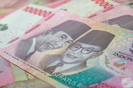 Close-up of Indonesian 100,000 Rupiah banknotes in pink tones.